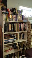 Books arranged on white shelving unit with multiple rows including hard and softcover titles.