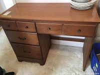 Wood desk, showing top and drawer front with round knobs and larger lower drawers with metal handles, one handle broken