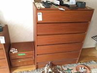 Front view of wood dresser with six drawers next to one of the matching small wood cabinets.