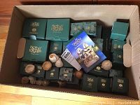 Cardboard box filled with sealed green Harmony Kingdom boxes and a few unboxed figurines laid on top