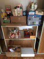 Photo showing a small beige wooden shelf holding various hygiene and toiletry bottles, a tissue box, and small storage baskets containing lotions and creams.