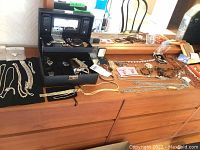 Overview of jewelry box and contents spread across wooden dresser