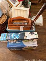 Spin mop in box, blue and white cooler, wooden basket, and packaging boxes visible.