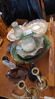Lot items on a table including glass bowls and plates, ceramic animal figurines, and brass candle holders