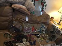 Multiple stained glass suncatchers on sofa including octagonal rose panel, round fairy panel, bird and butterfly shapes