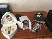Collection of assorted men’s and ladies wristwatches on table in various display boxes and loose with metal and leather bands.