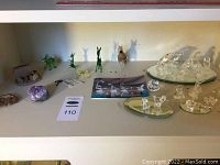Wide view of collection including green glass animals, amethyst crystal, Swarovski clear crystal animal figurines arranged on mirrored bases and plate.