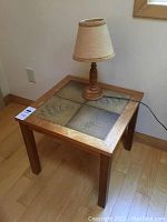 Front view of wooden end table with tile inlays and wood base lamp
