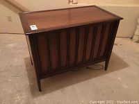 Closed view of the vintage RCA Victor TV cabinet showing the solid wood design with vertical paneling on the front and tapered legs.