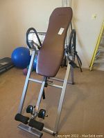 Front-left perspective of the inversion table showing padded backrest, foam foot supports, and frame structure