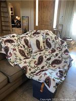 King size comforter with white base and paisley pattern displayed on sofa, showing two white king size pillows and two paisley patterned throw pillows