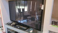 Front view of LG 64-inch flat-screen TV on stand reflecting room interior.