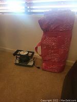 Medi-Rub Massager 2000 Plus device and folded red exercise mat with text next to it on carpet in front of window blinds.