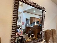 Full view of the square mirror showing the ornate wrought iron frame in a room.
