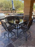 Full view of square glass-top table and four swivel chairs on outdoor patio