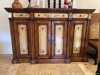 Front view of sideboard showing three drawers across the top and three cabinet doors below with cream painted panels and decorative motifs