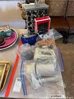 Photo of various kitchen items including boxed corkscrew set, blue stovetop kettle, cheese graters, hand mixers and spice rack jars in plastic bags