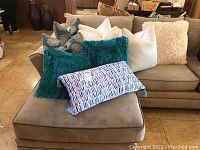 Full group of 10 pillows arranged on sofa with variety of colors and textures visible.