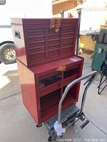 Front and side view of the two red metal tool boxes showing the upper toolbox with multiple drawers taped shut and the lower box with open shelves on wheels.