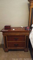Front view of wooden night stand showing two closed drawers, with items on top excluded from sale.
