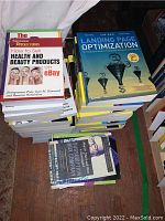 Books focused on eBay selling, health and beauty products, and online marketing strategies stacked in piles.
