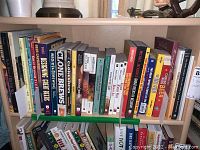 Photo showing a shelf with various books about brewing, beer, distilling, and humor including titles such as 'CLOSING TIME BEERS' and 'GLOBE BREWERS'.