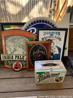 Full lot view including Avery Brewing India Pale sign, Jack Daniel's framed sign, bar art poster, blue bar mirror, and Pilsner Urquell tin box on a wooden deck surface.