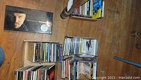 A view of several stacks and shelves of assorted CDs and a Garth Brooks boxed set on the floor.