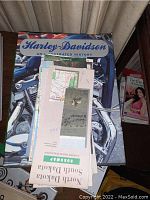 Harley-Davidson hardcover book with various paper roadmaps placed on top including a North Dakota South Dakota Roadmap.