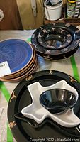 Lot includes blue ceramic plates, Texas-shaped black ceramic plates with gold decorative motifs, sectioned Texas-shaped serving piece with black bowl and white Texas-shaped serving bowls
