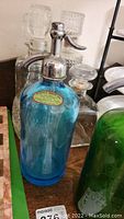 Blue vintage Schnolz Bros seltzer bottle with metal stopper and label visible