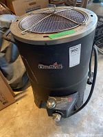 Front view of large black cylindrical metal turkey deep fryer with CharBroil logo and gas burner control knob attached at the base.