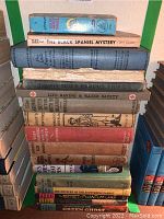 Stack of vintage hardcover books including The Black Spaniel Mystery, Thirty More Famous Stories Retold, Life Saving & Water Safety, and others.