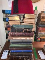 Stack of antique religious books with visible wear, some with gold-edged pages and various bindings.