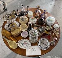 Full overview of the vintage feminine collectible items arranged on a round wooden table showing variety and quantity for the auction lot.