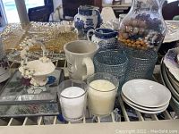 Wide view of assorted vintage items including porcelain dishes, mugs, glassware, candles, and decorative objects.