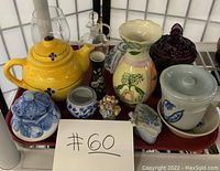 Photo of all vintage teapots, vases, jars, and collectibles arranged on a red tray, showing variety of colors and styles