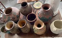 Photo showing top view of seven vintage pottery planters of various sizes, shapes and designs on wooden table.