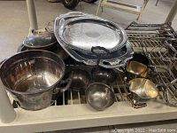 Wide shot showing the entire lot of silver-plated serveware items including trays, bowls, and creamers arranged on a shelf