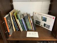 Shelf with a collection of 14 vintage and used books arranged upright including navigation charts on the right, with visible titles showing regional and maritime themes.
