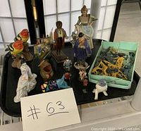 Photo showing the assorted vintage collectible items including birds, soldiers, and figurines arranged on a tray with a paper label #63