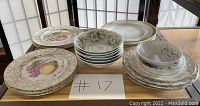 Top view of assorted vintage plates and bowls arranged on table with a note '#17'