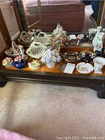 Photo showing a wooden shelf with various porcelain and ceramic items including baskets, floral figurines, and small vases.