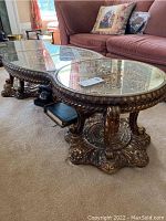 Side view of the ornate carved wood base and glass top coffee table showing the glass divided into three sections and curved design.