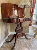 Full view of drop leaf table showing tabletop, drawer, harp motif base, and legs.