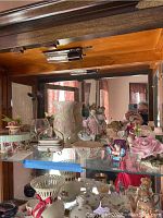 Display cabinet shelf showing multiple Lefton and Lenox porcelain figurines and decorative pieces including children figurines and boxes