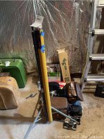 Overview of Knox panorama movie screen yellow carrying case with tripod stand and various camera bags on floor in storage area.