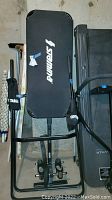Overhead view of folded black Stamina inversion table showing padded backrest with logo and metal frame.