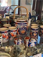 Porcelain tea set with teapot, tea cups, and lidded bowls with floral and geometric blue, red, orange designs.