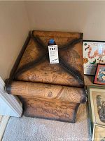 View of the storage trunk from the front showing the antique map design and reinforced dark trim edges.